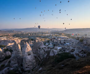 panorama sulle tipiche formazioni rocciose della cappadocia con le mongolfiere che le attraversano all'alba