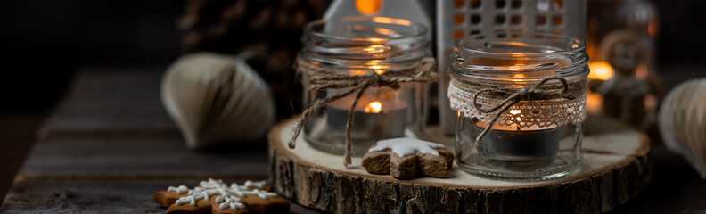 Banner. Aromatic christmas handmade candle with sweet scent of gingerbread cookies. Cozy holiday home atmosphere, aromatherapy. Interior composition with burning candles, anise, cinnamon, pine cones