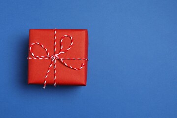 Beautiful gift box tied with bow on color background 