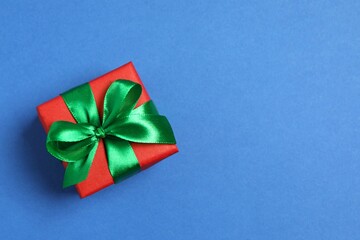 Beautiful gift box tied with bow on color background 