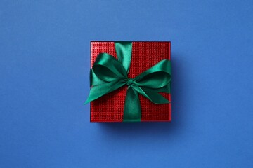 Beautiful gift box tied with bow on color background 