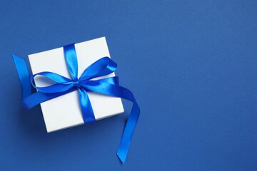 Beautiful gift box tied with bow on color background 