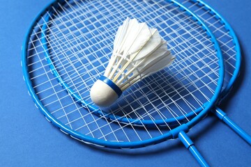 Badminton rackets and white badminton shuttlecock on color background