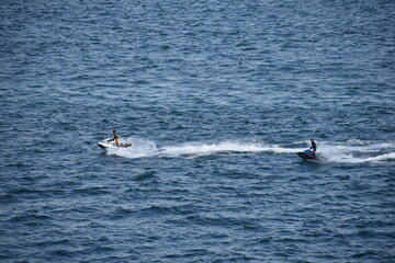 Naklejka premium Two people riding jet skis across the Bosphorus in Istanbul, speeding through the water and creating waves. The scene captures the thrill and energy of water sports on the city's famous waterway 