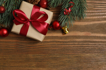 Beautiful gift box tied with bow and Christmas decorations on wooden background 
