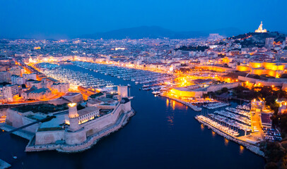 Fototapeta premium Aerial view of old port, Tour du Fanal and Basilica of Notre Dame at Marseille, France at night