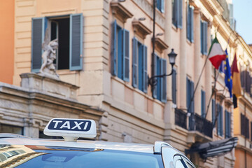 Italian Rome Taxi sign close-up view with the classic Roman street facade on the background