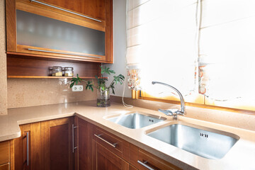 Kitchen with wooden furniture and stainless steel metal handles, beige granite countertop, double stainless steel sink and single-lever stainless steel faucet