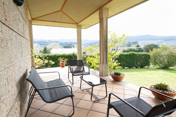 Terrace with porch in a country house, metal and black terrace table and chairs