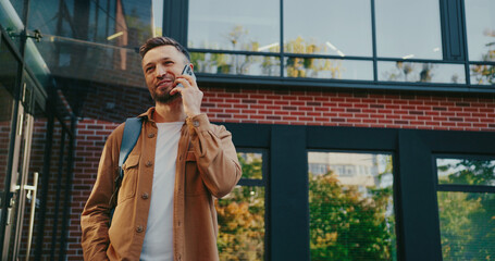 Caucasian man entering from modern building. Answering important call from friend or family on...