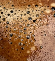 Close-up of bubbling liquid with foam and golden brown hues The macro shot highlights the detailed texture of carbonation, perfect for coffee, beer, or beverage-related backgrounds and designs