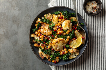 Roasted Cauliflower and roasted chickpeas salad, with pomegranate, kale, with spices, oil and lemon...