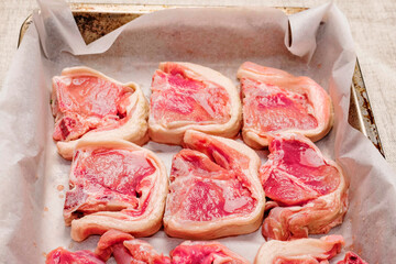 Juicy marinated lamb loin chops on a white cooking pater on a old rusty metal tray ready to go into oven. Meat product cooking. Fine high quality on the bone cut.