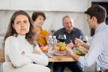 Upset young woman at family holiday table with parents at home. Unpleasant discussion