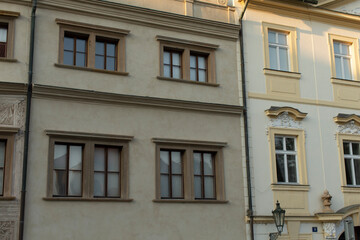 The facade of two historic buildings showcases intricate window designs, enhancing the urban landscape