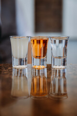 Three glasses of diverse drinks reflecting on a shiny surface for a modern beverage concept