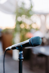 Close up of microphone on stand with blurred outdoor background, perfect for events and performances