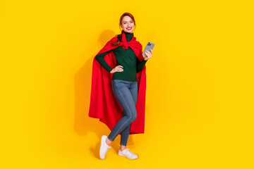 Full length photo of cheerful pretty lady dressed green jumper red mantle texting modern device empty space isolated yellow color background