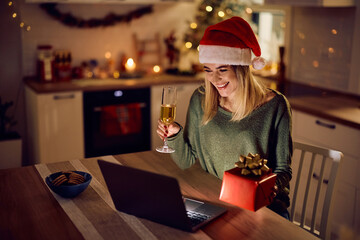 Happy woman toasting during video call on Christmas Eve.