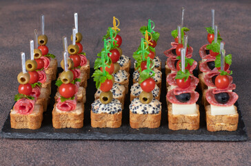 Assortment of canapes with cherry tomatoes, sausage, cheese, olives and seaweed caviar