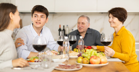 Father and mother together with adult children talking at the dinner table at home