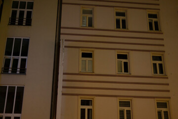 An illuminated apartment building at night, highlighting visible windows and intricate architecture