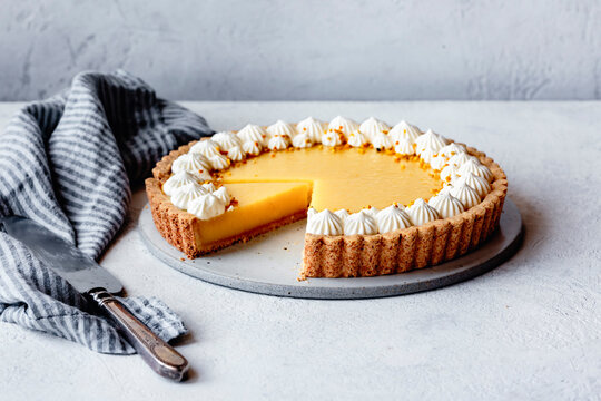Lemon tart on a plaster surface with piped whipped cream-11
