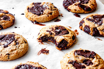 An assortment of freshly baked cookies with gooey chocolate chunks on a parchment paper.