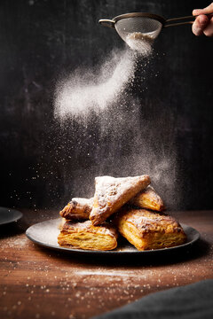 Apple Turnovers with Icing Sugar on Wooden Surface