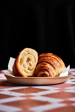 Croissant cut in half on tiled surface with napkin