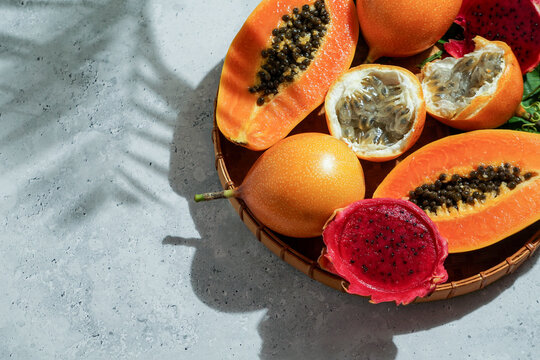 exotic tropical fruits,  passion fruits and dragon fruit, ripe papayas. on a bamboo tray with green leaves, stone background