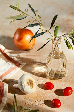Kitchen Still Life with an olive branch; garlic, onion and tomatoes.