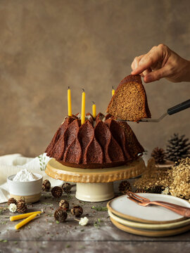 Christmas cake slice over a rustic table and moody scene. Presence of a hand