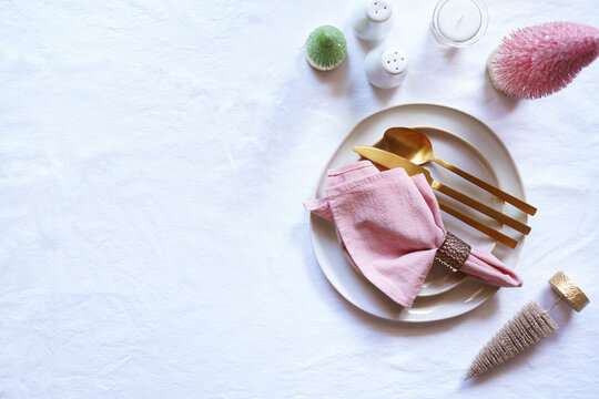 Christmas Dinner Table Setting in Modern Pink, White and Gold Theme. Horizontal Orientation with Negative Space.