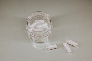 A glass jar containing capsules with notes of wishes, close-up on a gray background