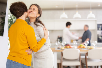 Happy mother meets her daughter, hugs and kisses her. In the background father shakes the guy hand