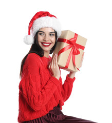 Woman in Santa hat and red sweater holding Christmas gift on white background