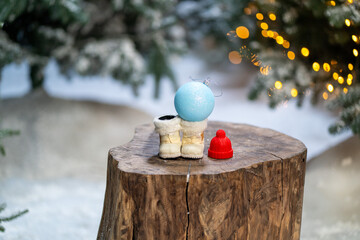 white santa claus boots and toys on tree stump in winter snowy forest . Merry Christmas and happy new year