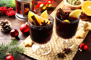 Tasty mulled wine with spices and Christmas decor on wooden table, closeup