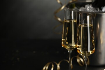 Champagne in glasses with decor on black table, closeup and space or text. Christmas celebration