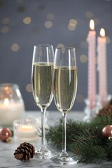 Delicious champagne in glasses and Christmas decor on marble table against blurred lights, closeup