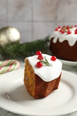 Traditional Christmas cake decorated with red currants and rosemary on table