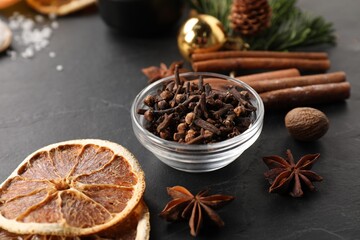Different aromatic spices on black table, closeup. Christmas season