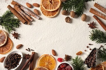 Frame of different aromatic spices and fir tree branches on table, flat lay with space for text. Christmas season