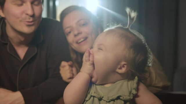 A little girl lets out a war cry and slaps herself in the mouth playing games with her parents before going to bed