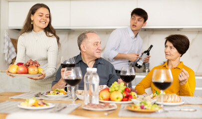 Father and mother together with adult children talking at the dinner table at home
