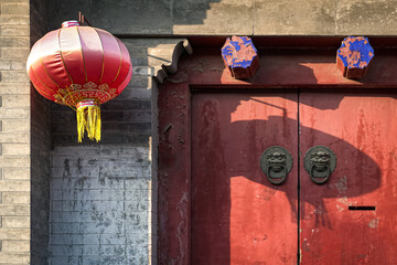 Traditional ancient old door in China with door knocker and red lantern.