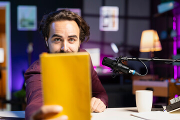 Content creator raising book in front of camera, paid by company to recommend it to viewers....