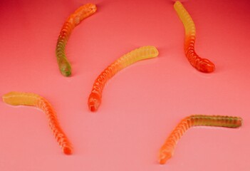 Jelly gummy worms close-up of different sweet flavors for children on a bright pink background