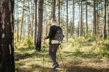 Fototapeta premium Young caucasian man hiking or trekking through the forest 